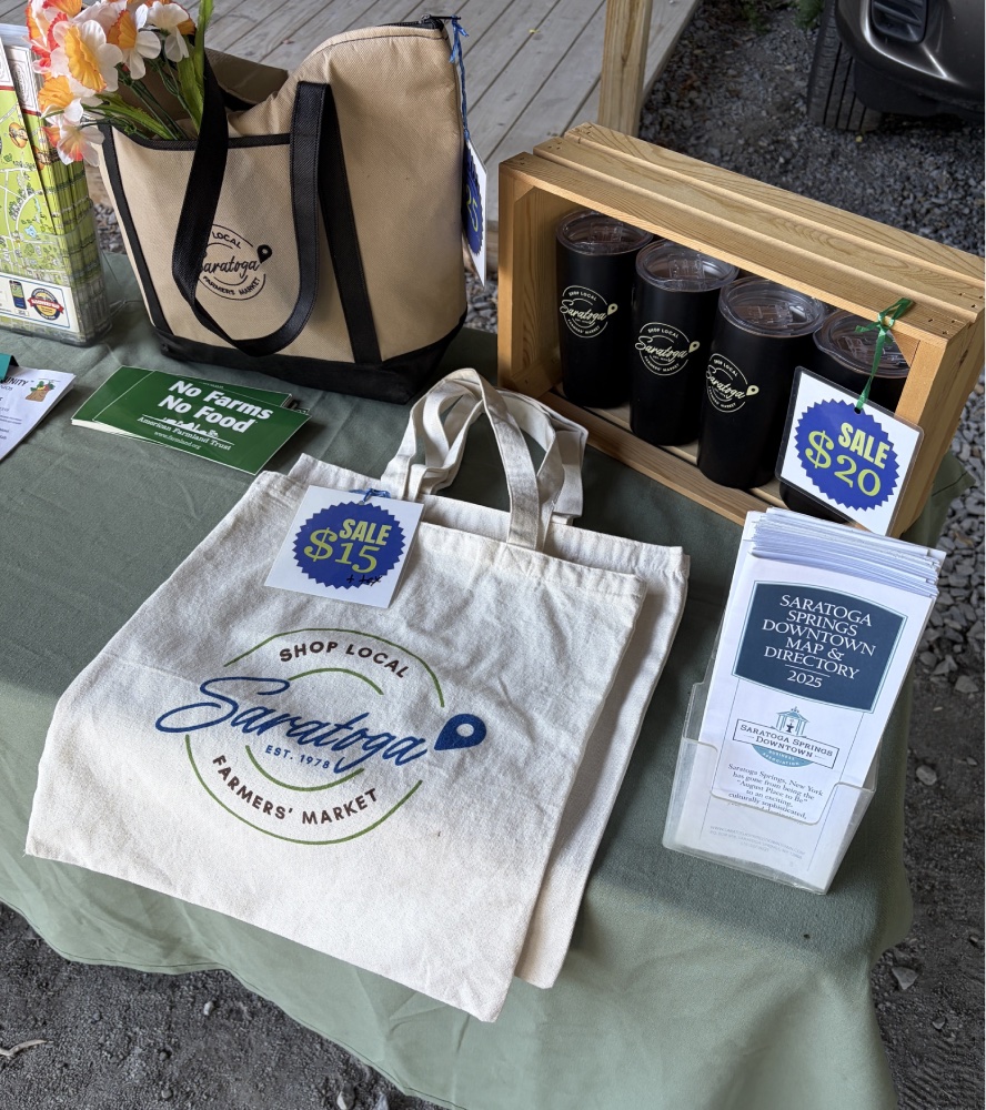 Merchandise (tote bags, tumblers) at Saratoga farmers market vendor table