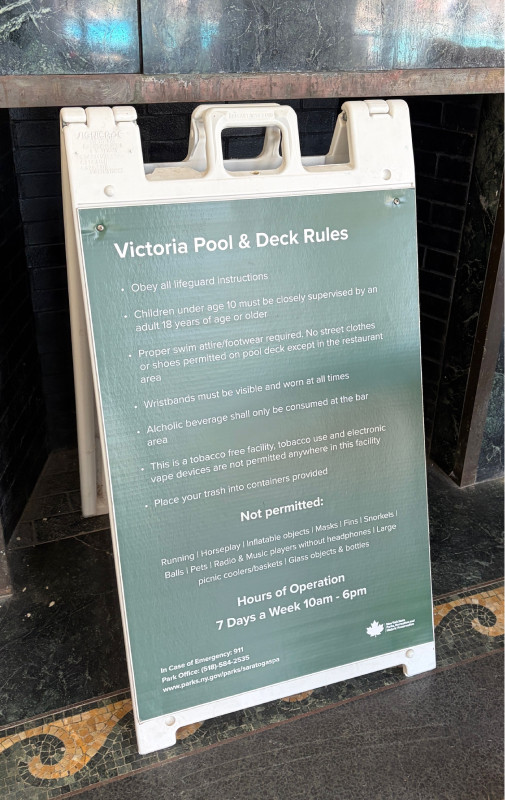 Green and white A-frame sign with Victoria Pool and Deck Rules listed.