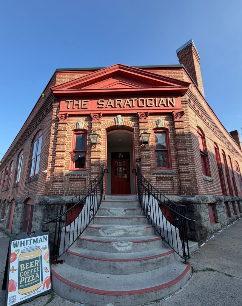 The red brick exterior of Whitman Brewing in Saratoga, with steps leading up to the entrance.