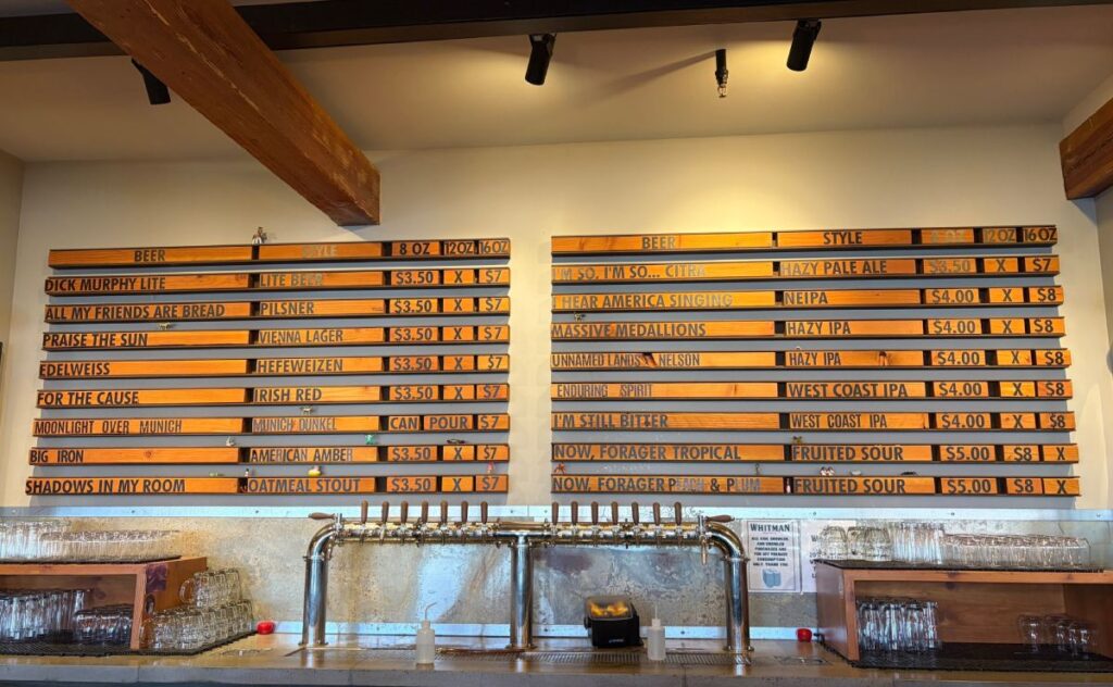 A row of draft beer taps beneath a wooden tap list menu at Whitman Brewing.